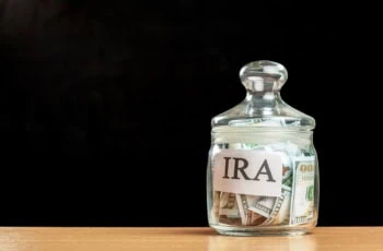 the word IRA is written on a glass jar with money in it.