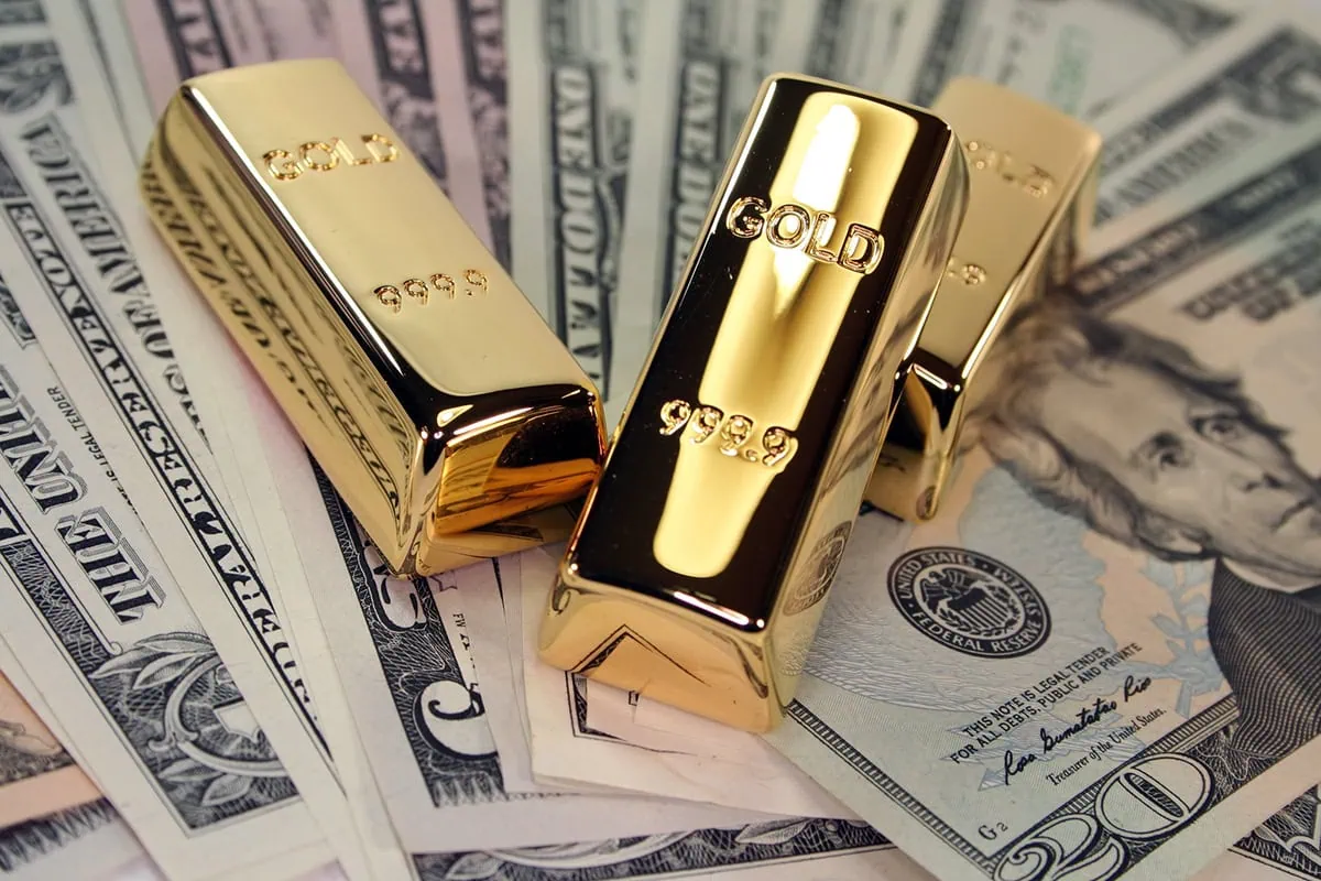 little gold bars on top of various us dollar bills.