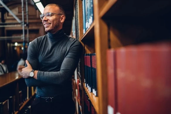 male standing by books jobs smiling