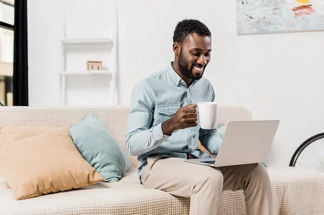 man happily looking at computer with coffee