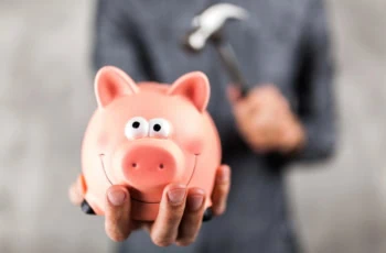 Man holding a piggy bank with hammer in background