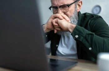 a man looks stressed as he views his laptop.