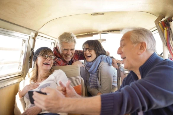 Group of senior friends in camper van using smartphone