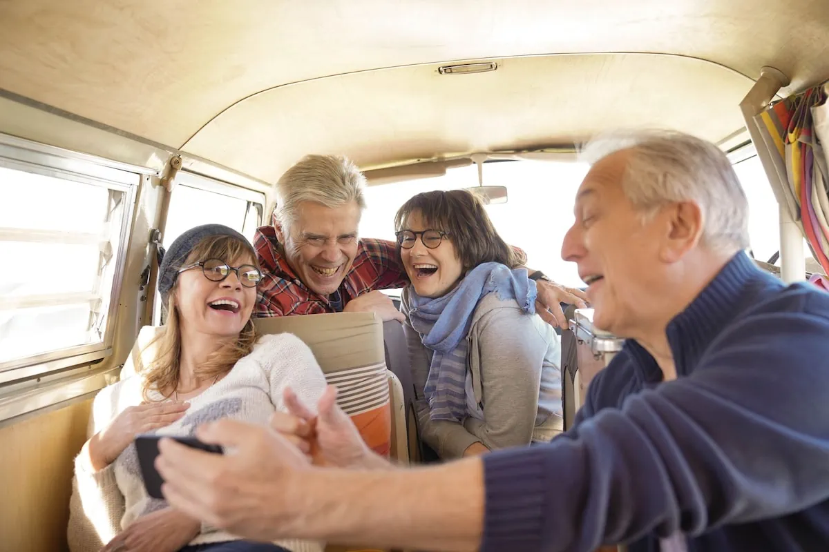 The Frugal Adventurer: 12 Premium Experiences That Cost Seniors Nothing 13 Group of senior friends in camper van using smartphone