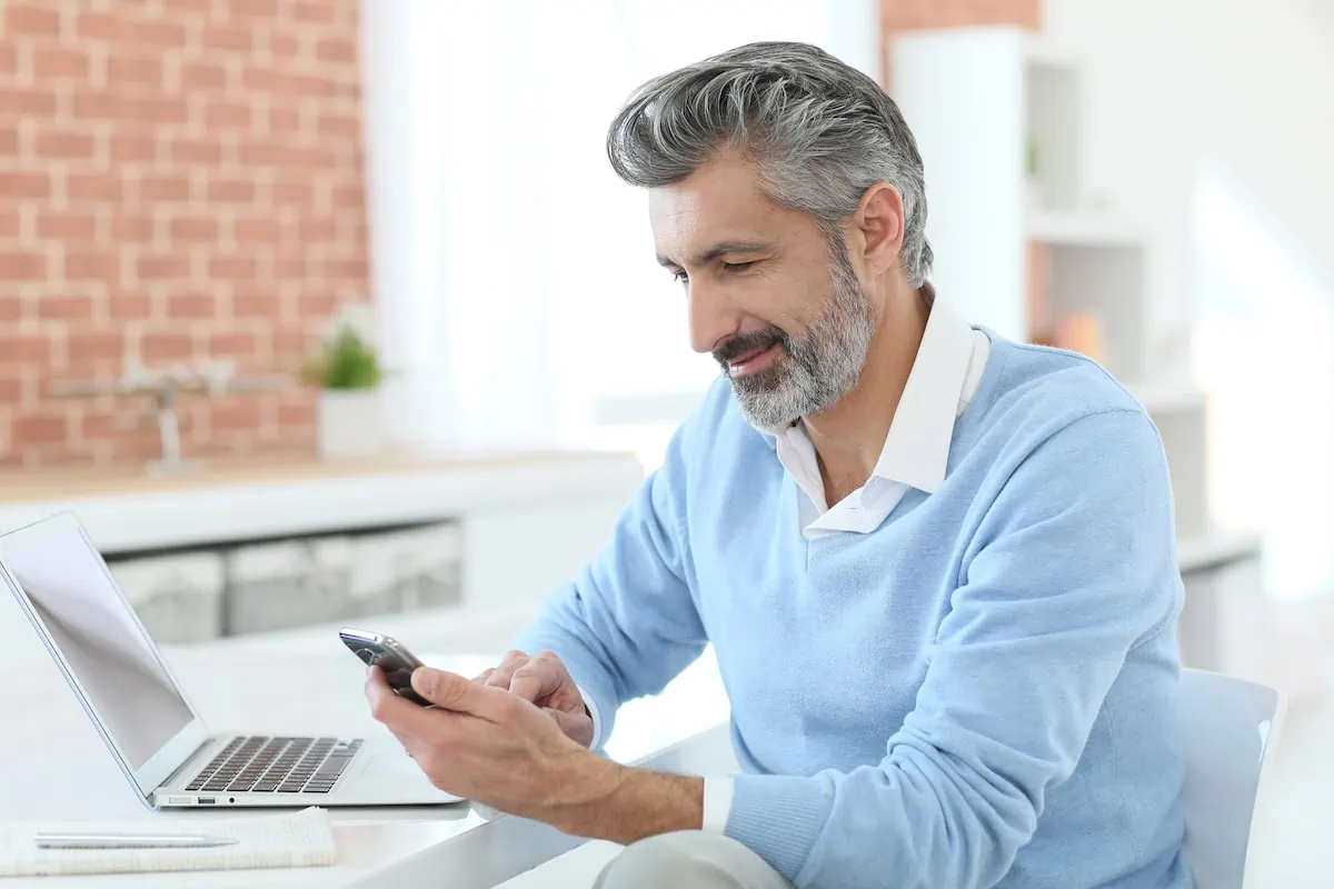 man looking at his phone and computer