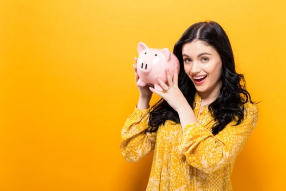 woman holding piggy bank while smiling