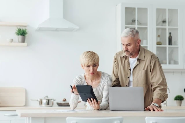 middle-aged couple looking at laptop and calculator