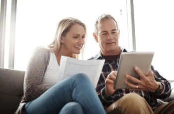 Home budgeting in the age of the app. a mature couple using a digital tablet while going through their paperwork together on the sofa at home.