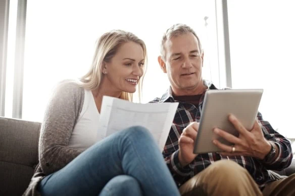 Home budgeting in the age of the app. a mature couple using a digital tablet while going through their paperwork together on the sofa at home.