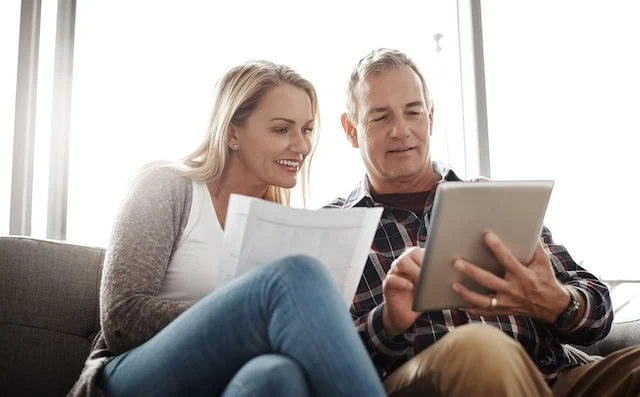 Home budgeting in the age of the app. a mature couple using a digital tablet while going through their paperwork together on the sofa at home.