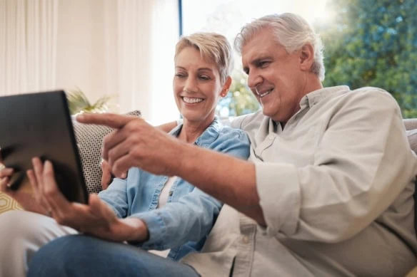 middle-aged couple looking at tablet together happy on the couch