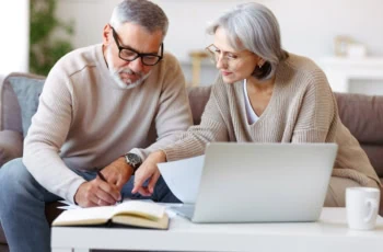 Smiling senior couple calculate expenses or planning budget together, reading notification letter with good news from bank , retired family husband and wife paying bills online on laptop