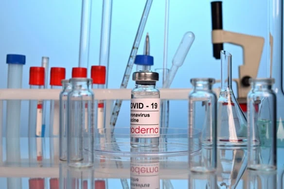 A vial of Moderna's COVID-19 vaccine sits on a lab table.