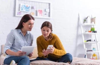 mother mom daughter kid teen tablet smartphone couch living room 1200