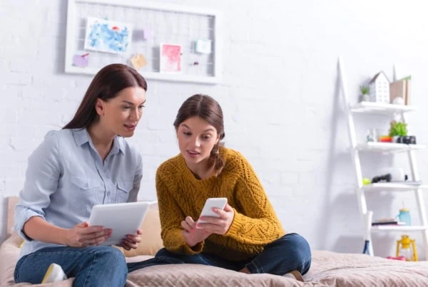 mother mom daughter kid teen tablet smartphone couch living room 1200