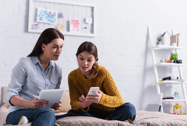 mother mom daughter kid teen tablet smartphone couch living room