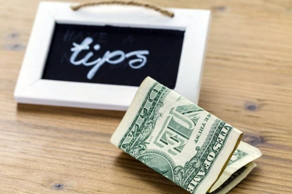 a chalkboard that says tips and a one dollar bill near it.