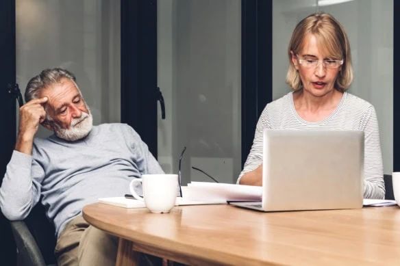 Senior couple reading documents and calculating bills to pay in living room at home