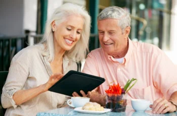 Senior Couple Using Tablet Computer At Outdoor Café
