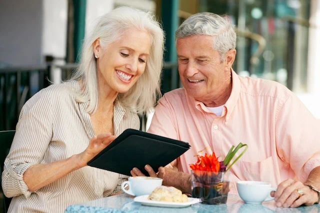 Senior Couple Using Tablet Computer At Outdoor Café