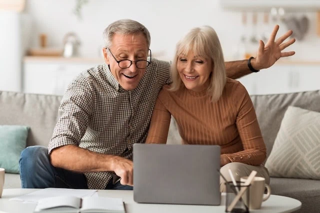 senior spouses smiling at computer happy