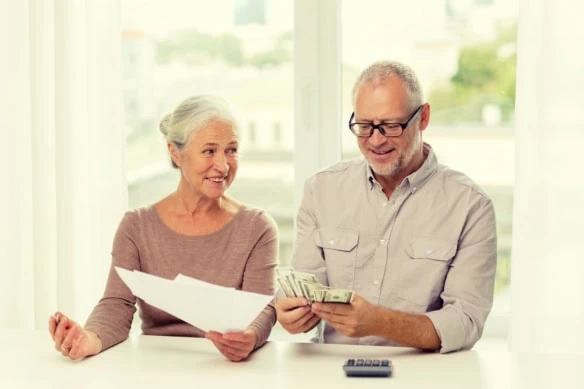 senior couple with money and calculator at home