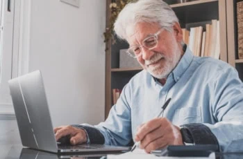 Happy old businessman smiling working online