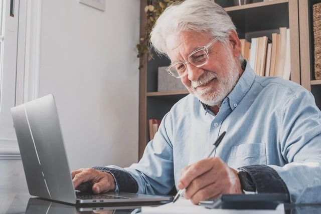 Happy old businessman smiling working online