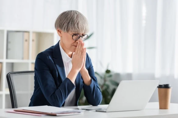 older woman looking at laptop in disappointment