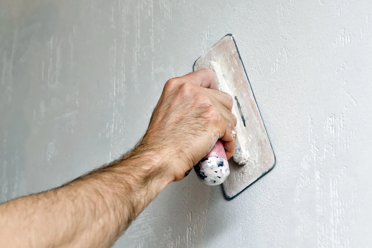 The Retirement Leak: 7 Invisible Expenses Draining Your Nest Egg 3 a man uses a trowel to plaster an interior wall.