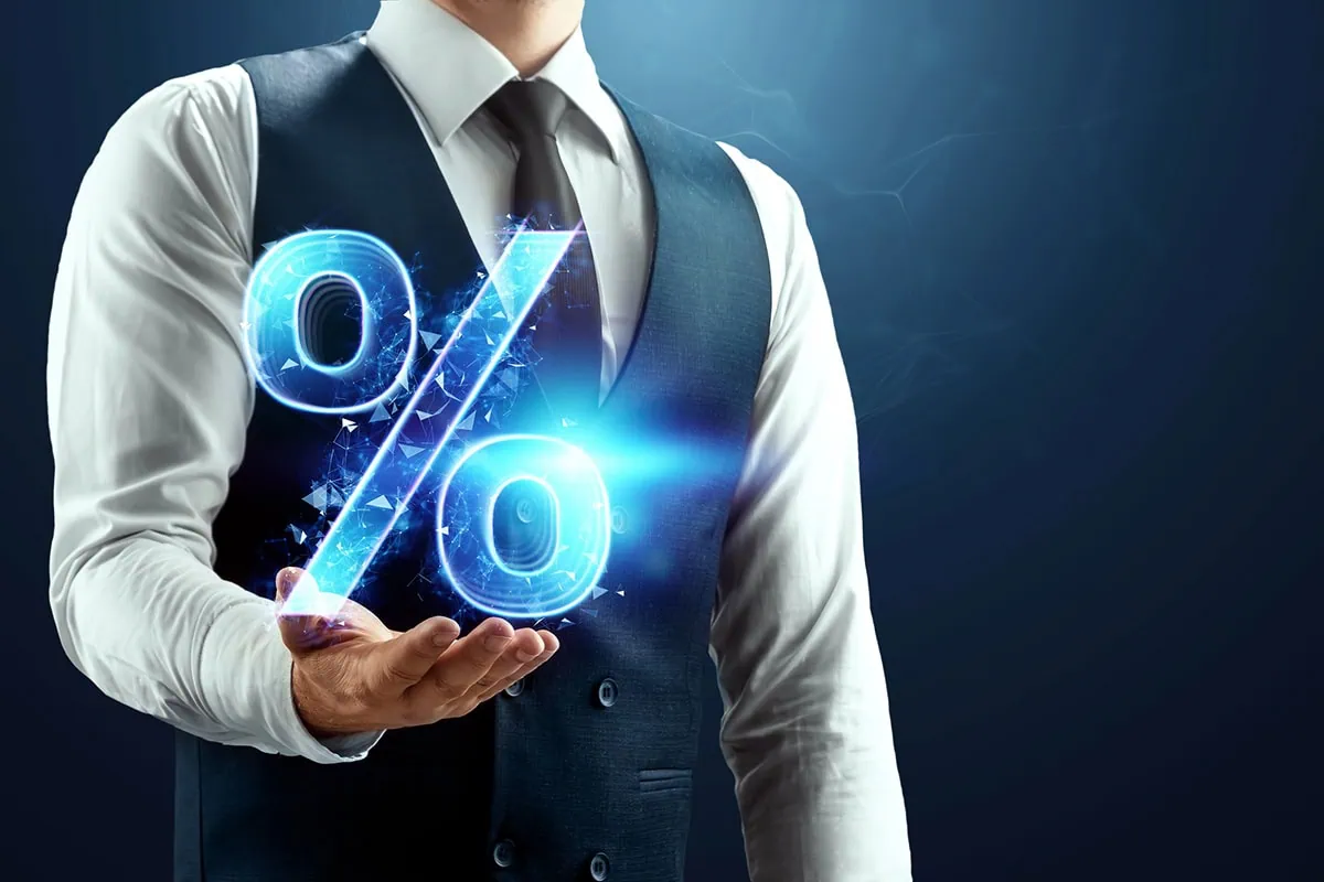 a businessman holds up a virtual percent sign.