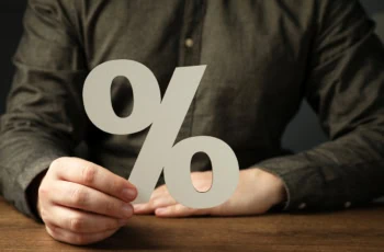 a person holding a cutout of a percent sign 1200.