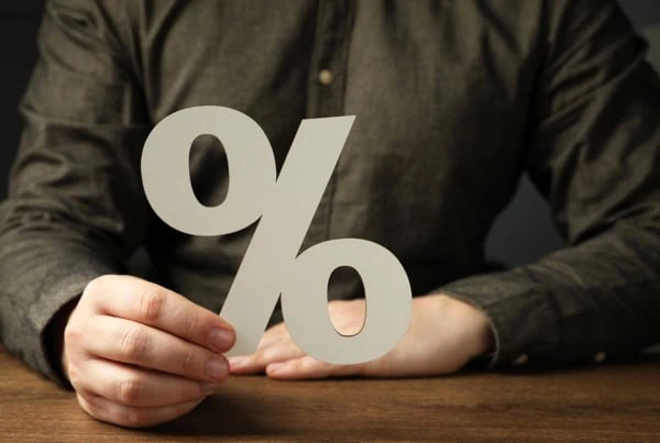 a person holding a cutout of a percent sign 1200.