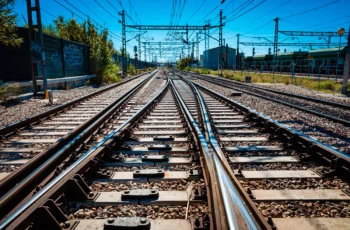 a low-angle photograph of train tracks during a clear day with a blue sky.