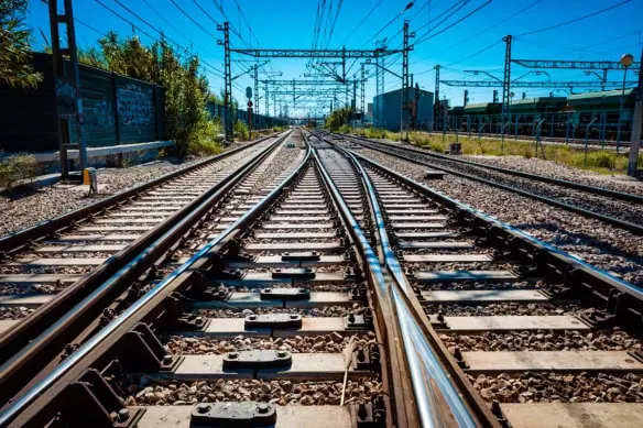 a low-angle photograph of train tracks during a clear day with a blue sky.