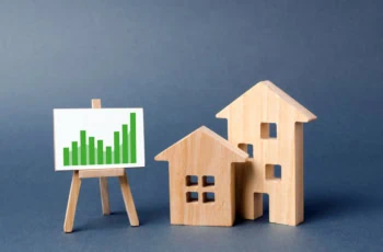 Wooden figures of houses and a poster with information charts with a tendency of sales growth. Increase liquidity and attractiveness of assets. rent or cost of buying a home. real estate value growth.