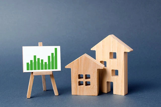 Wooden figures of houses and a poster with information charts with a tendency of sales growth. Increase liquidity and attractiveness of assets. rent or cost of buying a home. real estate value growth.