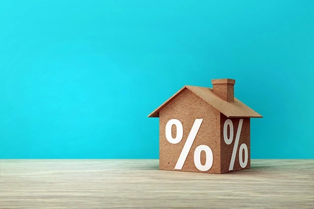 Creative idea of house model paper and percentage sign symbol icon on wooden table.