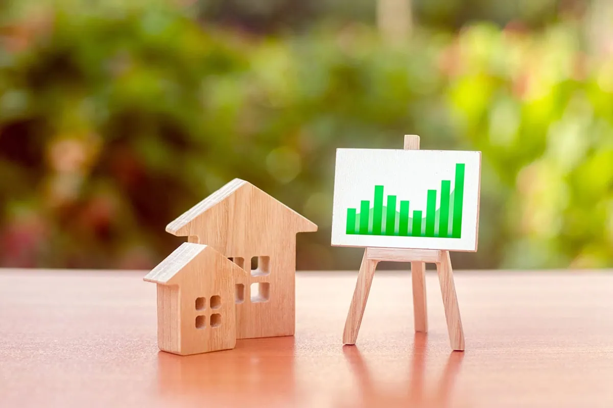 wooden houses and a chart showing growth on an easel.