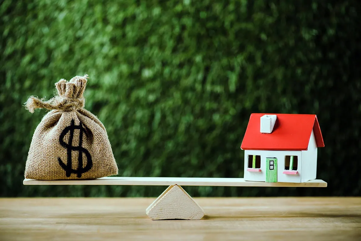 Liquid Growth or Locked-In Gains? Choosing Between REITs and Private Placements 8 a bag of cash and a house sit on opposite sides of a seesaw.