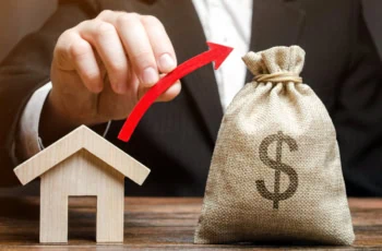 a man draws a virtual arrow from a model of a house to a small sack of cash.