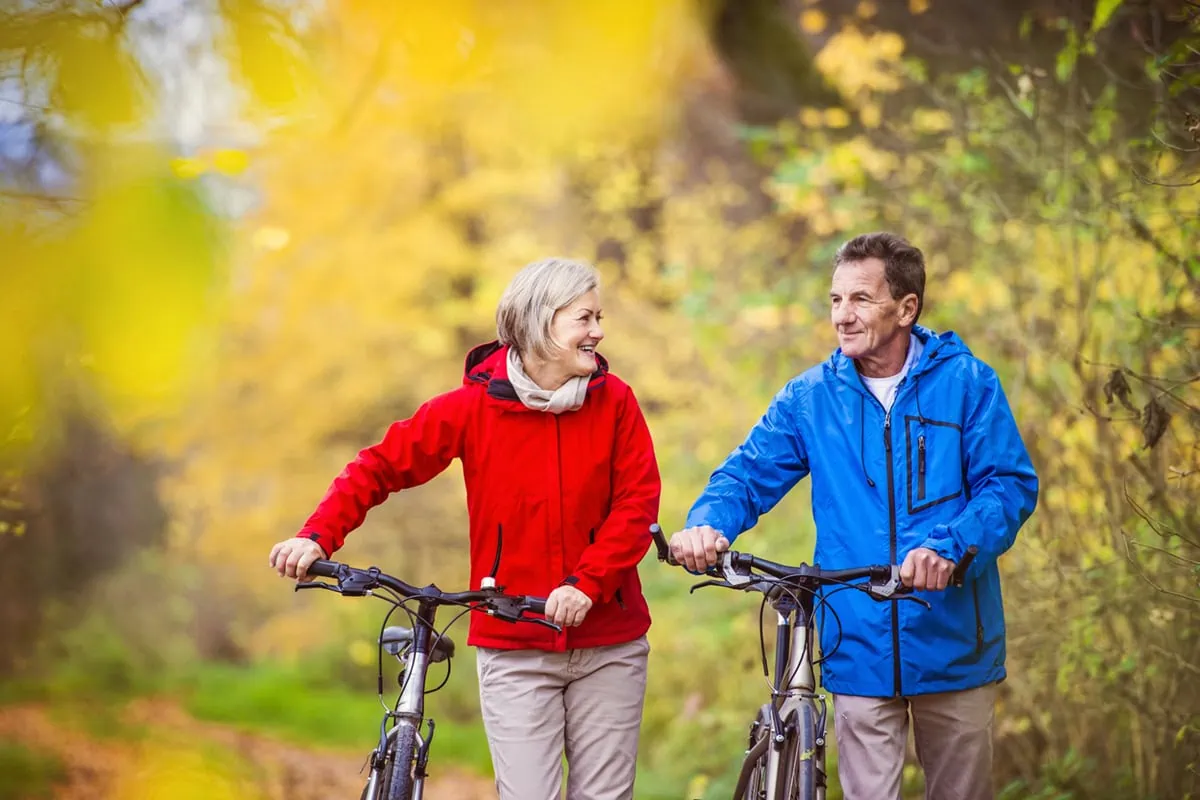 Put Your Budget on Diet by Cutting These 25 Expenses 24 an older couple walk their bikes along a path.