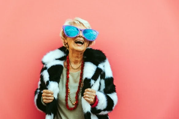 an older woman with comically large sunglasses celebrates.