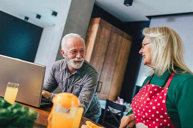 a happy retired couple spends time in the kitchen together.