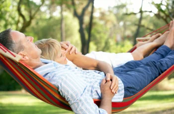 an older couple relaxes in a hammock.