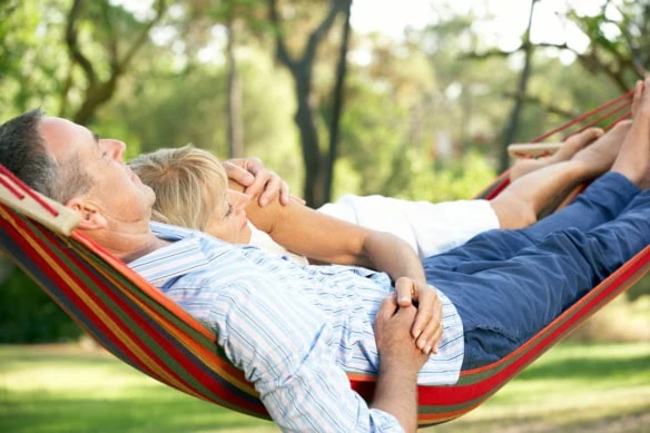 an older couple relaxes in a hammock.