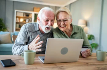 an older couple getting excited while looking at a laptop screen.