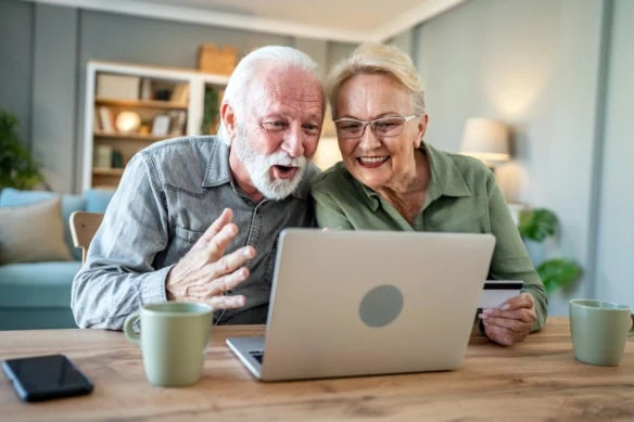 an older couple getting excited while looking at a laptop screen.