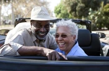 Portrait of senior couple at the back seat of their car smiling.