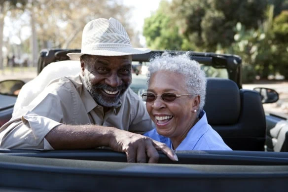 Portrait of senior couple at the back seat of their car smiling.